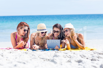 Happy friends wearing sun glasses and using tablet