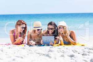 Happy friends wearing sun glasses and using tablet