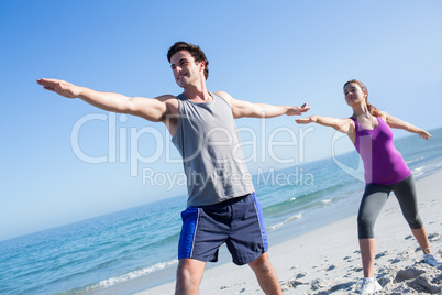 Happy couple doing yoga beside the water