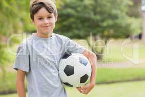 Smiling boy holding a soccer ball in the park
