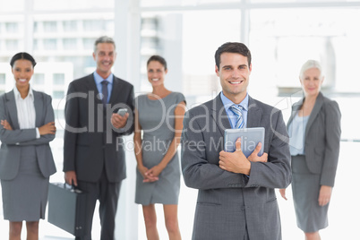 Businessman using digital tablet with colleagues behind