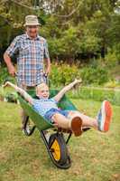 Happy grandfather and his granddaughter with a wheelbarrow