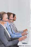 Business team working on computers and wearing headsets