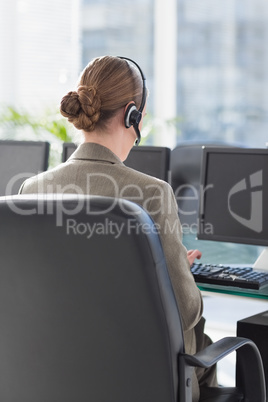 Smiling businesswoman with headset using computers