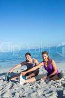 Happy couple stretching together beside the water