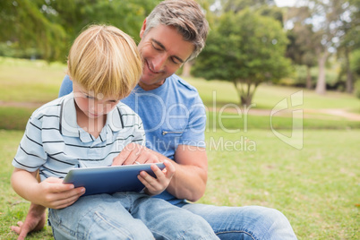 Happy father with his son using tablet in the park Happy father with his son using tablet in the park