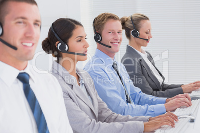 Business team working on computers and wearing headsets