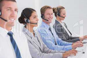 Business team working on computers and wearing headsets