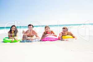 Happy friends lying on inflatable mattress above the water