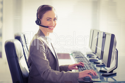 Smiling businesswoman with headset using computers