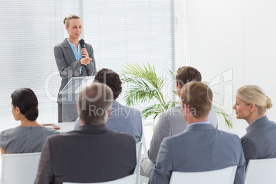 Pretty businesswoman talking in microphone during conference