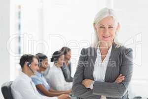 Businesswoman with arms crossed and executives using computers