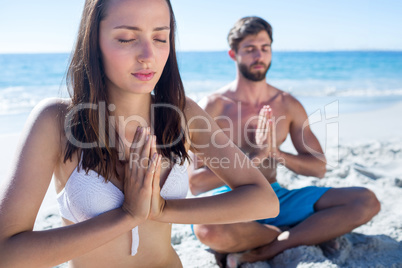 Happy couple doing yoga beside the water