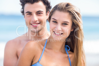 Happy couple in swimsuit looking at camera and embracing