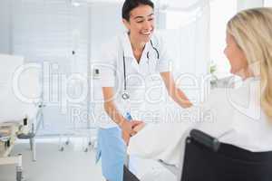 Happy doctor smiling at her patient in wheelchair