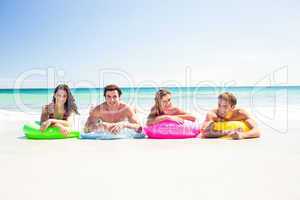 Happy friends lying on inflatable mattress above the water