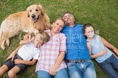 Happy family smiling at the camera with their dog