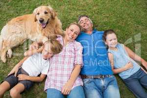Happy family smiling at the camera with their dog