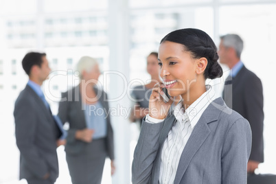 Businesswoman using mobile phone with colleagues behind