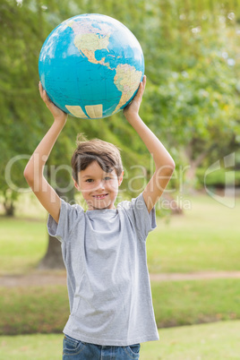 Smiling boy holding an earth globe in the park