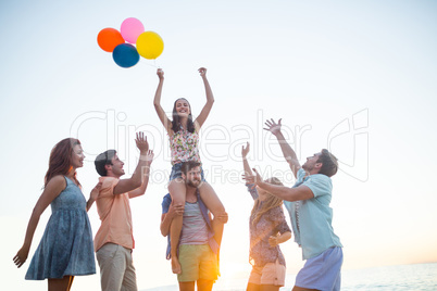 Happy friends dancing on the sand with balloon