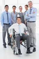 Businessman in wheelchair with his colleagues looking at camera