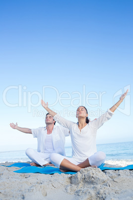 Happy couple doing yoga beside the water