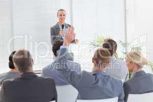 Pretty businesswoman talking in microphone during conference