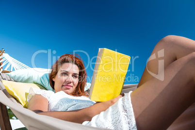 Brunette reading a book while relaxing in the hammock