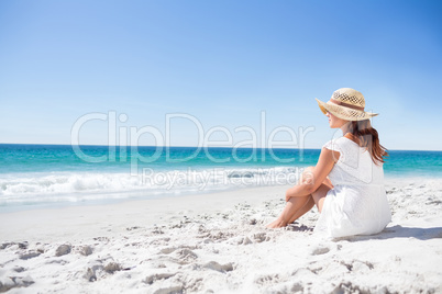 Brunette sitting in the sand and looking at the sea