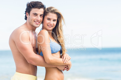 Happy couple in swimsuit looking at camera and embracing