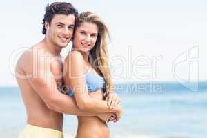 Happy couple in swimsuit looking at camera and embracing