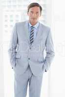 portrait of businessman looking at camera with hands in pockets