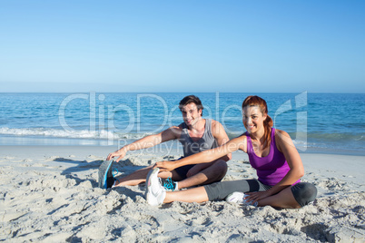 Happy couple stretching together beside the water