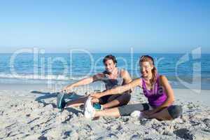 Happy couple stretching together beside the water