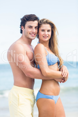 Happy couple in swimsuit looking at camera and embracing