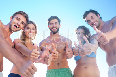 Happy friends smiling at camera showing thumbs up