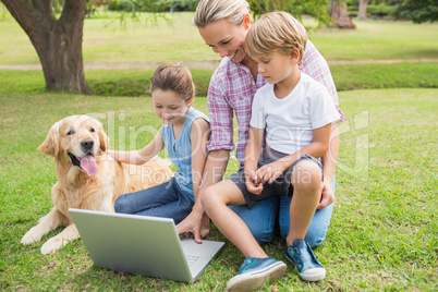 Happy family with their dog using laptop