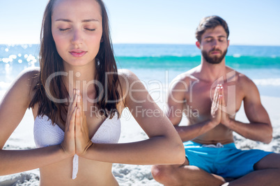 Happy couple doing yoga beside the water