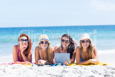 Happy friends wearing sun glasses and using tablet