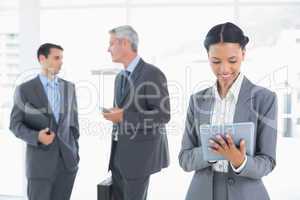 Businesswoman using a tablet with colleagues behind