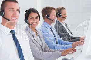 Business team working on computers and wearing headsets