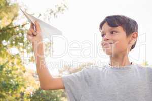 Smiling boy with paper plane in the park