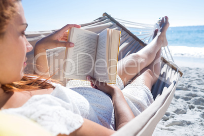 Brunette reading a book while relaxing in the hammock