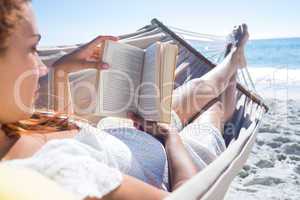 Brunette reading a book while relaxing in the hammock