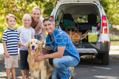 Happy family smiling at the camera with their dog