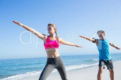 Happy couple doing yoga beside the water