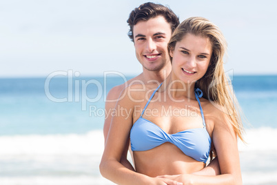 Happy couple in swimsuit looking at camera and embracing