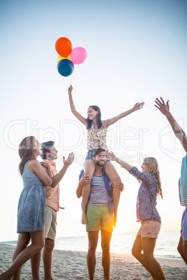 Happy friends dancing on the sand with balloon