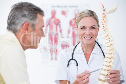 Smiling doctor showing her patient a spine model